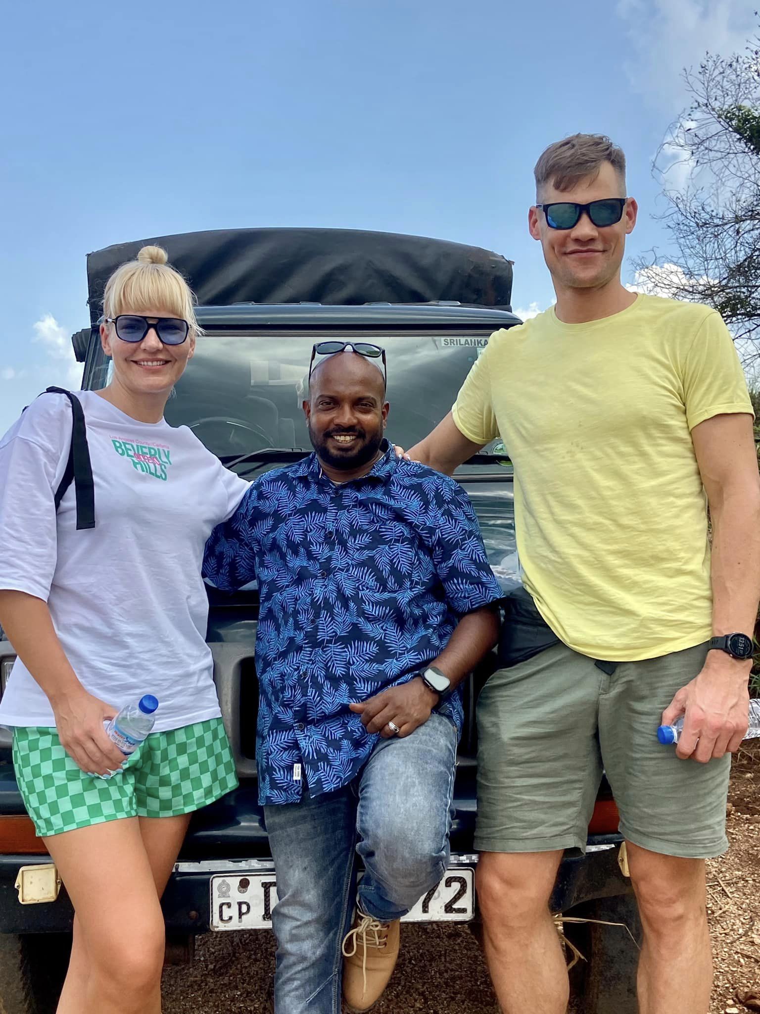 Three travellers posing beside a tour van
