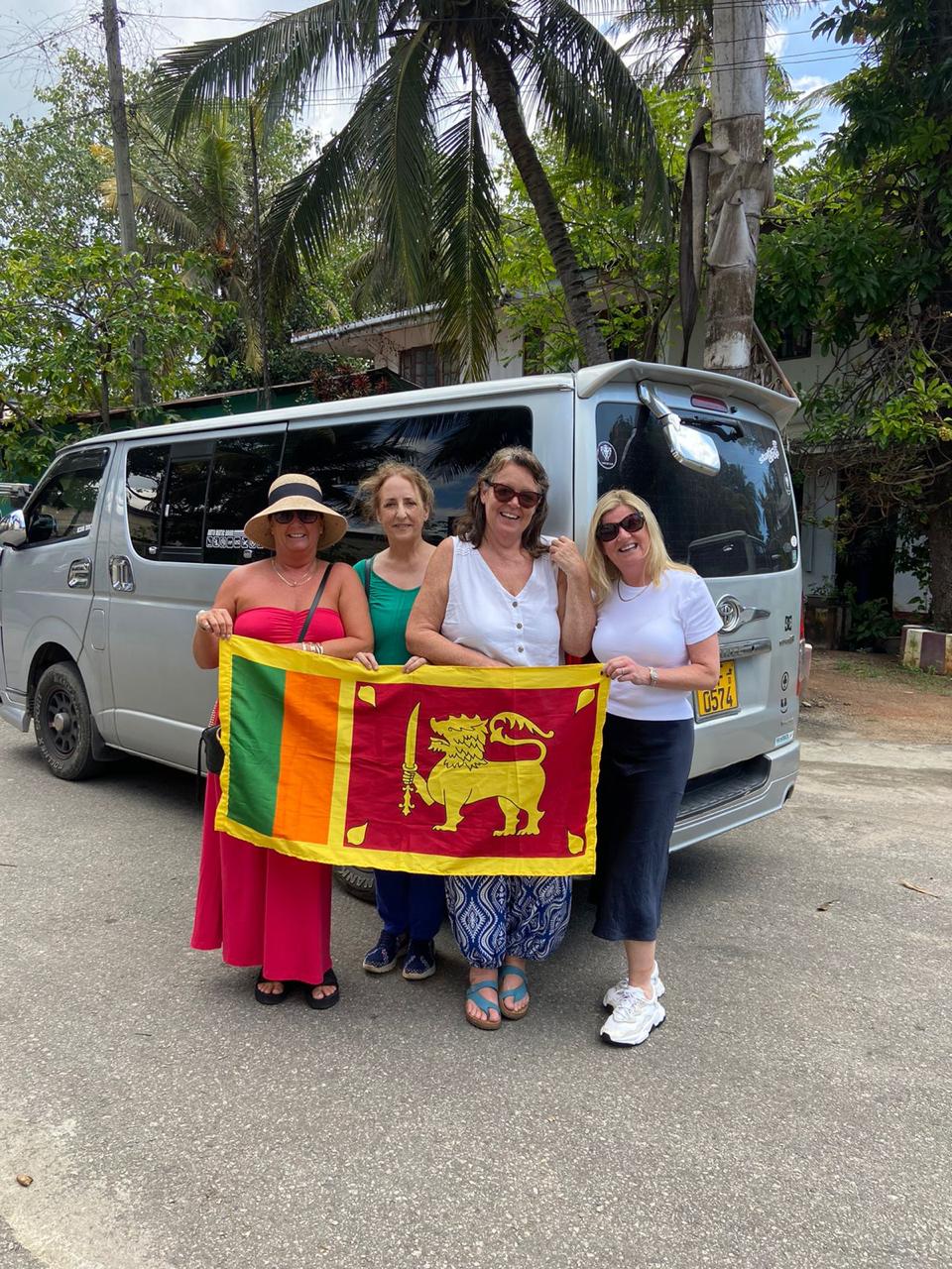 Travellers holding a Sri Lankan flag beside their van