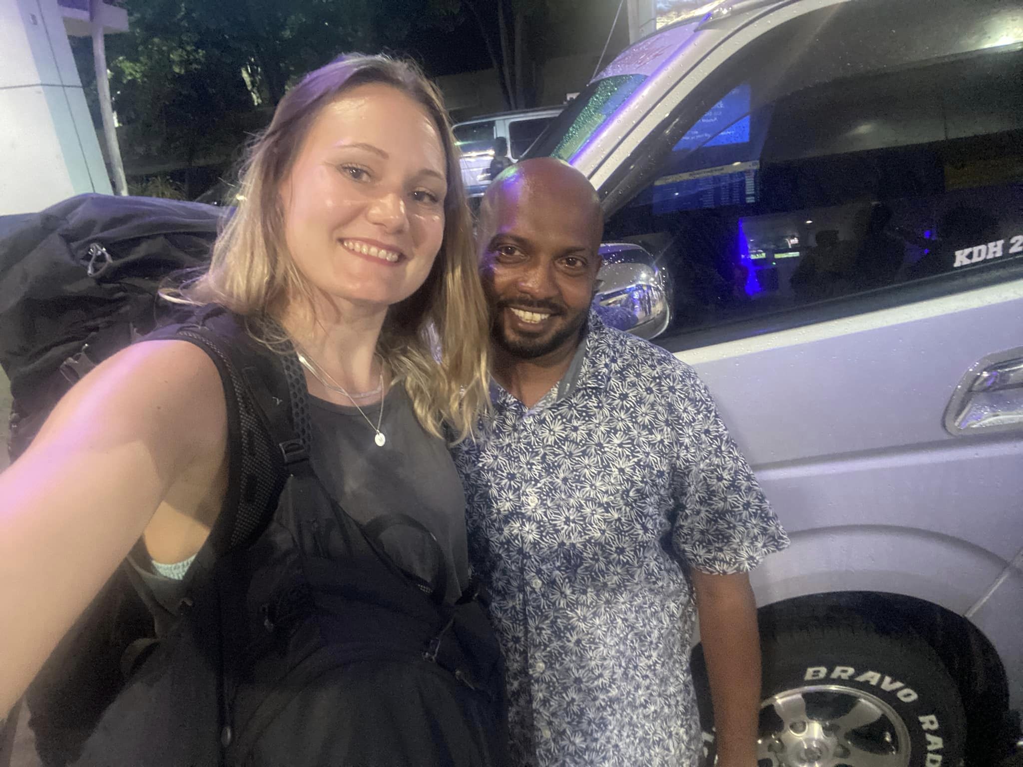Two travellers taking a photo beside a van at night