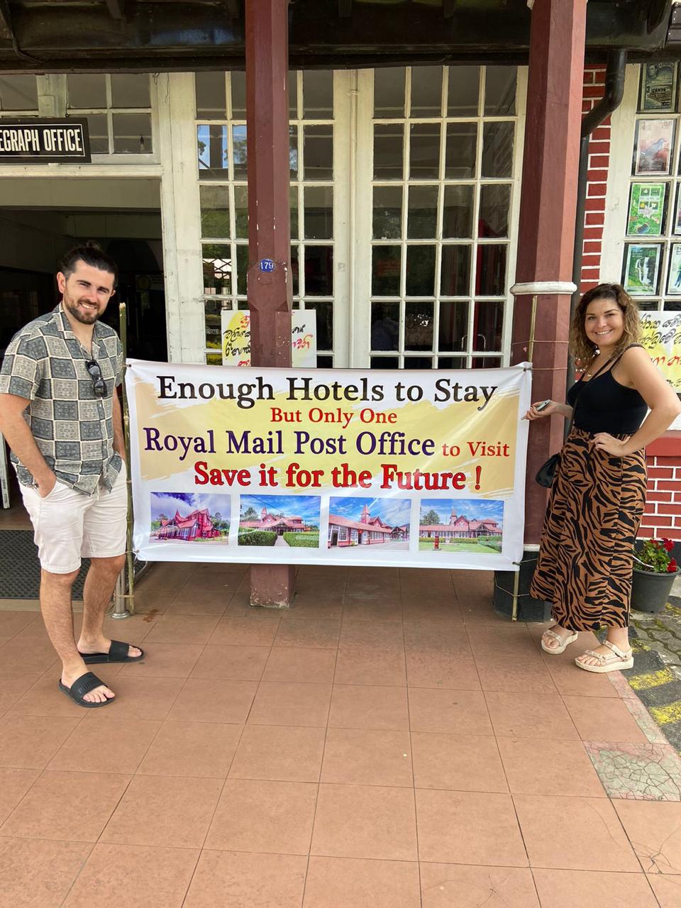 Visitors posing outside a building with a travel banner
