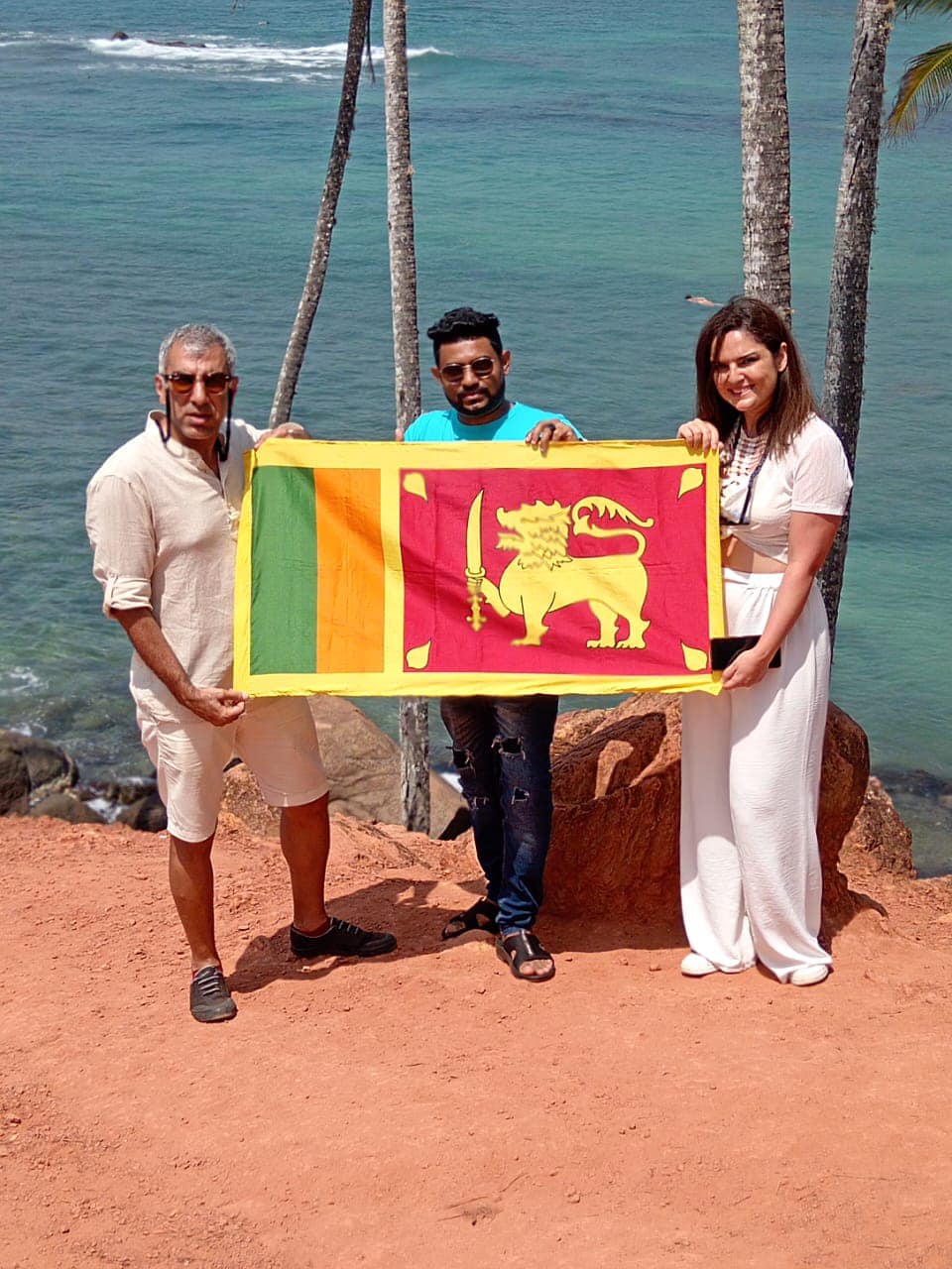 Travellers holding a Sri Lankan flag beside the coast